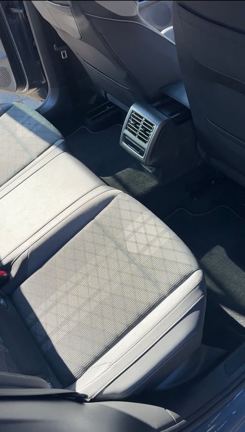 Car interior showing front passenger seat with white and gray upholstery and air vents visible on dashboard