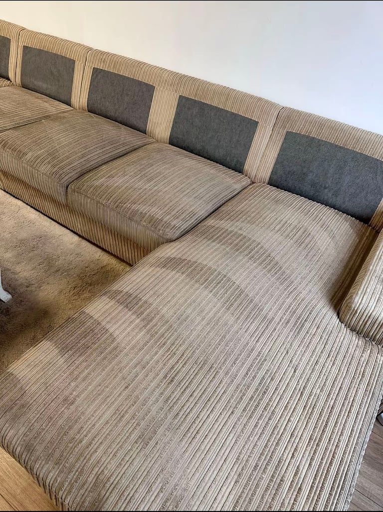 Modern sectional sofa with beige ribbed fabric and dark gray cushioned backrest in a minimalist living room setting